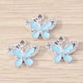 Vista macro di ciondoli a farfalla in smalto azzurro con bordi argentati e piccoli strass - Farfalla Blu (YD1695yinlan) / Confezione da 10 / Argento