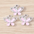 Dettaglio di ciondoli a farfalla in smalto rosa con bordi argentati e piccoli strass - Farfalla Rosa (YD1695yinfen) / Confezione da 10 / Argento