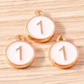 Macro detail of three rose gold number 1 enamel charms on a light wood background - 10 Pieces Pack / Pink Number 1 (YD1814fense1)
