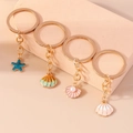 Set de 4 llaveros de temática oceánica con estrellas de mar y conchas esmaltadas oro - Juego de Colgantes Océano