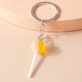 Detail view of a yellow and white resin lollipop keychain with a silver metal flat ring - Yellow