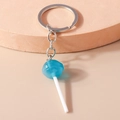 Detailed close-up of blue lollipop keychain made of translucent resin on beige stand - Blue