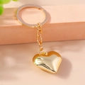Polierter goldener Herzanhänger Schlüsselanhänger auf rosa Podest, kreativer Metallschmuck - Gold