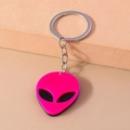 Close-up of pink alien keychain with metallic ring on a minimalist peach background - Rose Red
