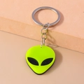 Close-up of a neon green alien head keychain with a polished silver metal ring - Yellow