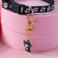 Detail of black nylon pet collar with paw print and enamel cat pendant on pink stand - Black