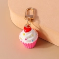 Nahaufnahme eines Cupcake-Schlüsselanhängers mit weißem Frosting und goldenem Clip - Rosa