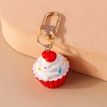 Detailaufnahme eines Cupcake-Schlüsselanhängers mit Cremehaube und goldenem Karabinerhaken - Rot