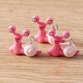 Drei niedliche rosa Schnecken-Anhänger aus Kunstharz auf hellem Holzhintergrund - Rosa