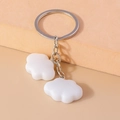 Detailed macro view of two cute white cloud charms on a silver metal keychain ring - White