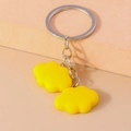Close-up of cute yellow resin cloud keychains with silver metal rings on a warm surface - Yellow