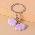 Detail of purple cloud pendants on a silver metal keyring against orange background - Purple