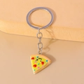 Simpatico portachiavi a fetta di pizza con faccina ammiccante e condimenti colorati su beige - Pizza Shape