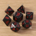 Detail von 7-teiligen polyedrischen Würfelanhängern mit silbernen Ösen und roten Zahlen - 7er-Pack Set / Schwarz Rot
