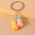 Close-up of cute baby bottle keychains with colorful silicone charms and silver rings - Pink