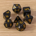 Detail von 7 schwarzen polyedrischen Würfelanhängern mit Goldzahlen und Metallringen - 7er-Pack Set / Schwarz und Gelb