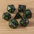 Nahaufnahme von 7 schwarz-grünen polyedrischen Würfelanhängern mit Silberringen - 7er-Pack Set / Dunkelgrün