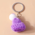 Detailed close-up of a purple knitted mini hat keychain with a white pom-pom detail - Purple