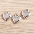 Close-up of three 3D silver heart pendants with smooth metallic finish on wood background - Silver