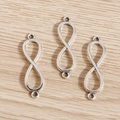Three silver infinity symbol alloy charms with double loops on a natural wooden background - Silver
