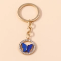 Portachiavi a farfalla dorata con strass bianchi brillanti e ali in acrilico blu - Blu