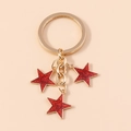 Dettaglio di un portachiavi dorato con tre ciondoli a stella rossi e glitterati - Rosso (YZ175hongse)