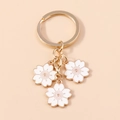Süßer minimalistischer Gold-Kirschblüten-Schlüsselanhänger mit drei weißen Emaille-Blumen - Weiß