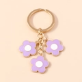 Goldener Schlüsselanhänger mit drei lila Kirschblüten-Anhängern aus Emaille - Lila