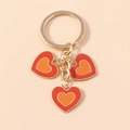 Porte-clés doré avec trois pendentifs en forme de cœur rouge et orange émaillé - Orange