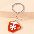 Close-up of red glitter resin mug keychain with white snowflake pattern and silver ring - Red Cup