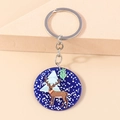 Detail of Christmas reindeer acrylic keychain with silver metal ring on cream background - Blue Elk