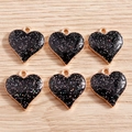 Gros plan de pendentifs cœurs noirs pailletés avec bordure dorée sur fond de bois - Noir