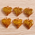 Macro shot of six gold heart-shaped pendants with glitter resin inlay for DIY jewelry - Yellow