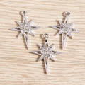 Macro shot of silver eight-point star pendants with sparkling rhinestones and top loops - Silver