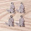 Dettaglio macro di quattro ciondoli a farfalla in argento con strass bianchi e ali cave - Confezione da 10 / Argento