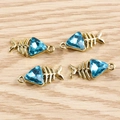 Detailed view of four golden fishbone pendants with blue crystal stones on wood - 10 Pieces Pack / Blue