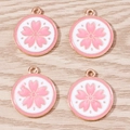 Detail showing four pink cherry blossom alloy charms with rose gold edges on wood surface - 10 Pieces Pack / Pink Cherry Blossom