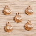Five gold-plated alloy shell charms for jewelry making on light wood surface - Gold