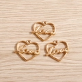 Dettaglio di tre ciondoli a cuore dorati Love per la creazione di gioielli DIY - Oro