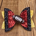 Detailaufnahme einer glitzernden Haarschleife mit Football-Motiv auf Holzhintergrund - Football-Mom-Stil / Rot Schwarz Gelb Stil (MC6548)