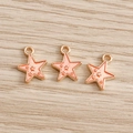 Macro detail of three pink enamel star pendants with golden alloy frames on wood - 10 Pieces Pack / Orange Pink
