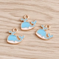 Detailed close-up of blue and white enamel whale pendants for DIY jewelry making - Blue