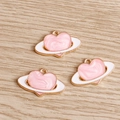Dettaglio dei ciondoli a pianeta cuore in smalto rosa con base in metallo dorato per fai-da-te - Rosa