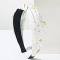 Close-up of white knotted headband with yellow star and moon print on twill fabric - White