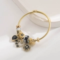 Detailansicht des goldenen Perlenarmbands mit schwarzen Herzanhängern und Blumen - Schwarz