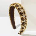 Detailed shot of wide padded headband featuring crystals and white floral embellishments - Brown