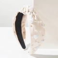 Dettaglio ravvicinato del cerchietto beige con perle, cuori e un nodo elegante - Beige