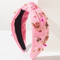 Dettaglio fascia rosa in tessuto con perle, strass e ciondoli a cuore con LOVE - Rosa