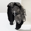 Luxurious black velvet headband with sparkling rhinestone flower on white stage - Black