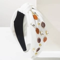 Detail eines weißen Knotenstirnbands mit Rugby-Anhängern und Kristallen auf Stativ - Weiß (Kaffee Ball)